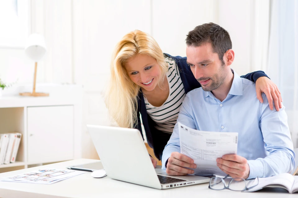 Couple souriant consultant des documents financiers dans un bureau moderne