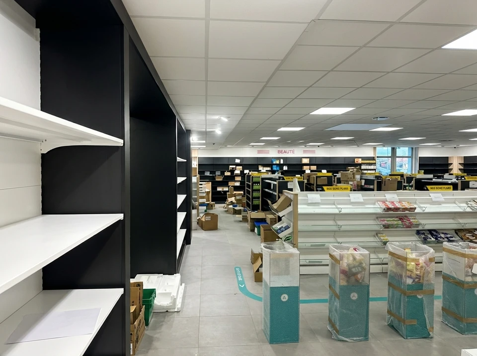 Espace de travail d'électricien avec plans techniques détaillés, multimètre numérique affichant des mesures, disjoncteurs modulaires, LED circulaire, câbles électriques colorés et composants électroniques