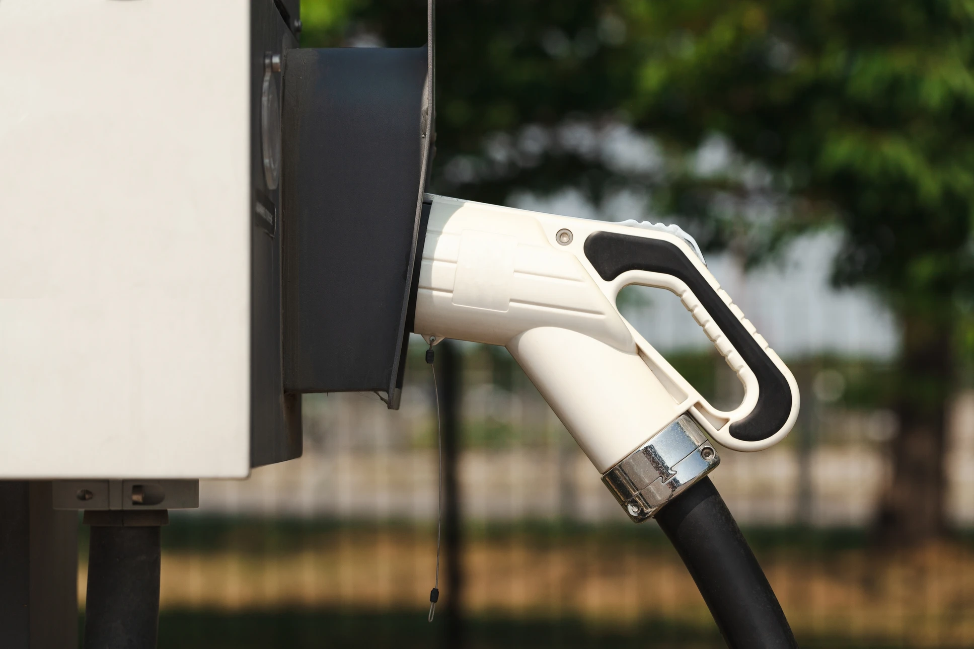 Scène extérieure moderne avec voiture électrique blanche en charge devant maison contemporaine à deux niveaux